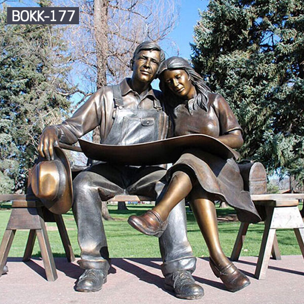 A couple is sitting on bench reading maps together metal outdoor sculptures