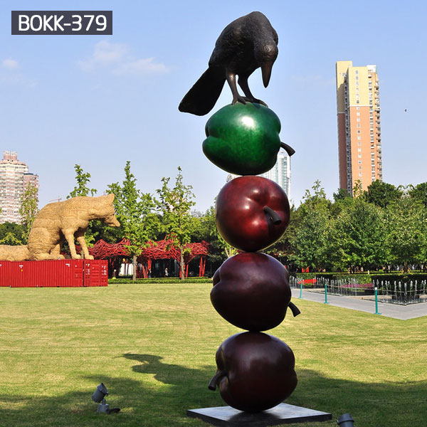 A bird standing at four apple bronze sculptures outdoor